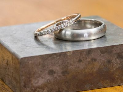 Diamond wedding band and brushed metal wedding ring displayed on a jeweller's steel block