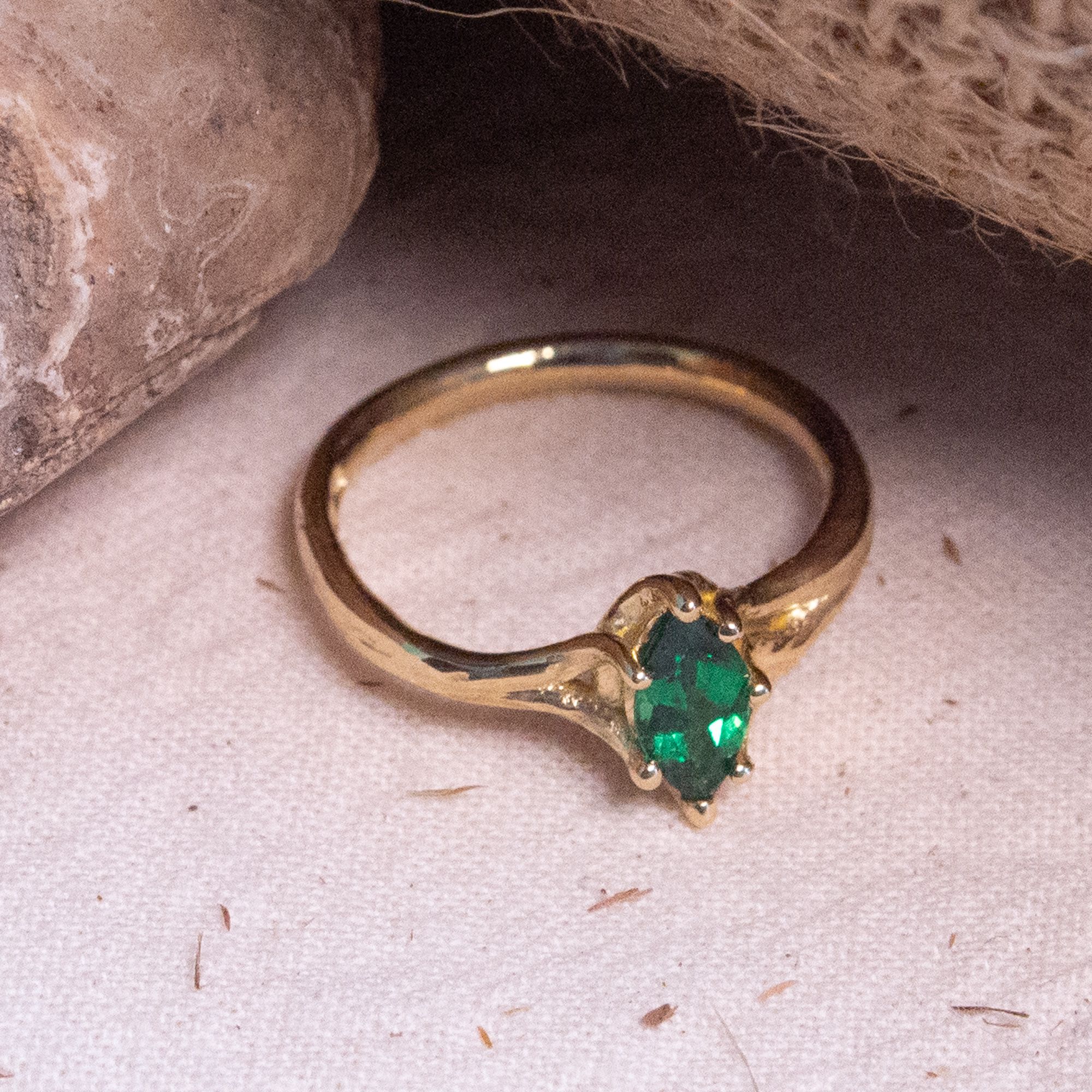 Close up of a goldsmith hand finishing a diamond engagement ring at the bench in a Wiltshire workshop, filing the setting in recycled precious metal