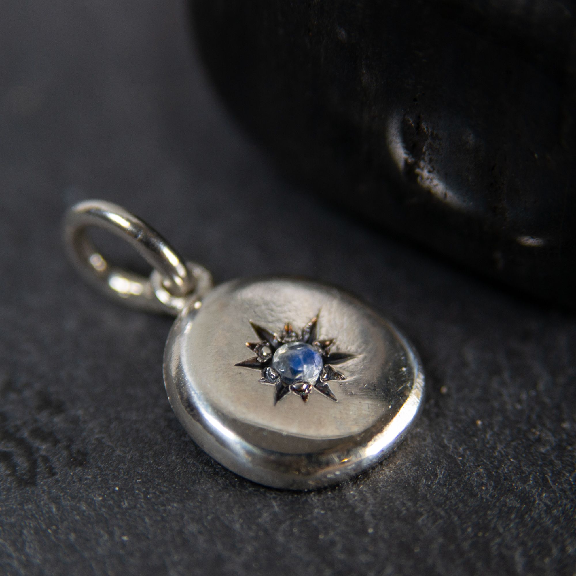 Seidr Frum Birthstone Charm in sterling silver set with moonstone shown on dark stone background