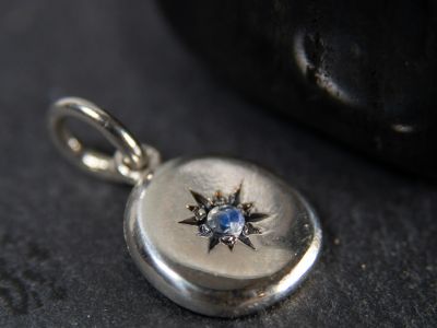 Seidr Frum Birthstone Charm in sterling silver set with moonstone shown on dark stone background