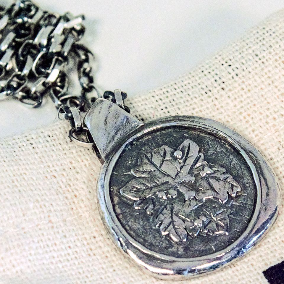 Angled view of sterling silver Green Man pendant showing sculptural depth and textured rim detail