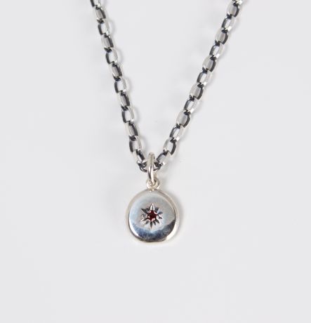 Seidr Frum Birthstone Charm in recycled sterling silver set with garnet shown on chain, a small pebble talisman handcrafted in Wiltshire